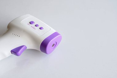 Beyaz masa arka planında yakın plan kızılötesi termometre. Üst Manzara. metin için ayrıntı