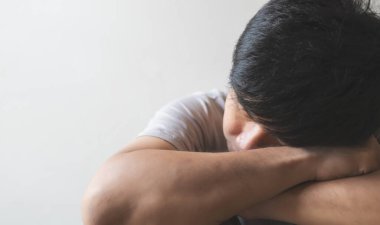 Yalnız başına oturan yakın plan bir pişmanlık ya da korku hisseden ve elini yüzünü odaya daldıran adam. yumuşak odaklı ve arka plandaki ışığın üzerinde