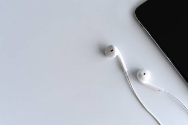 akıllı telefon ve kulaklık ışık arka plan üzerinde beyaz masada