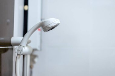 white shower head in a bathroom with soft-focus and over light in the background