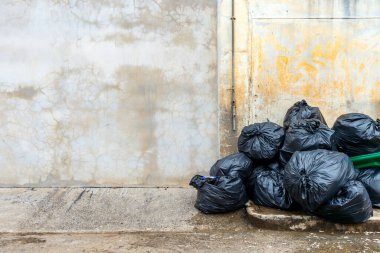 Eski tuğla duvarlı siyah çöp torbası.