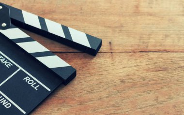 film director's desk. clapboard, book and digital camera on wood table with soft-focus and over light in the background 