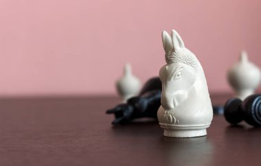 Arkaplanda ışık ve yumuşak odaklı ahşap masa üzerinde satranç oyunu