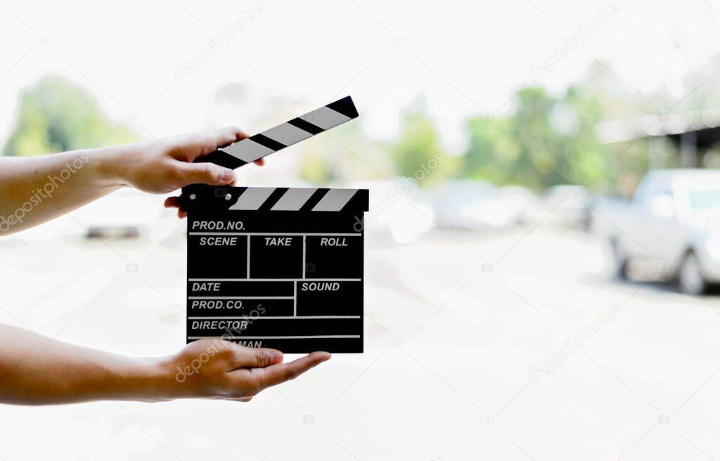 closeup man hands holding film clapper with soft-focus and over light in the background