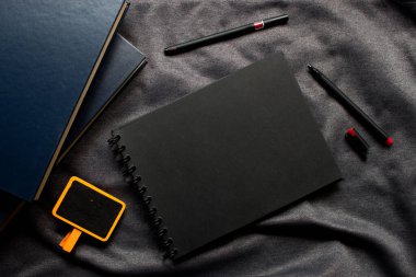 Siyah defter, kırmızı kalp ve arka planda ışık olan gri kumaşlı kalem. Metin için boşluk