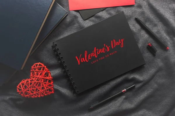 幸せなバレンタインデーのコンセプトブラックブックレッドハートペングレーの布に背景にライトがついています — ストック写真