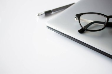 Ofis malzemeleri, bilgisayar ve gözlüklü beyaz masa, üst görünüm, arka planda ışık ve yumuşak odak