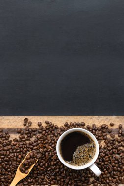Siyah ahşap masa arkasında bir fincan kahve ve fasulye. en üstteki görünüm