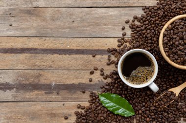 Siyah ahşap masa arkasında bir fincan kahve ve fasulye. en üstteki görünüm