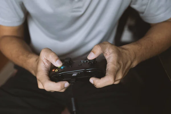 Stock image closeup hand man holding black joystick. play game. soft-focus and over light in the background