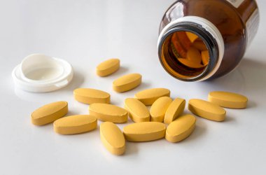 Beyaz masadaki C vitamini tabletlerini kapat. Yumuşak odaklı ve arka plandaki ışığın üzerinde.