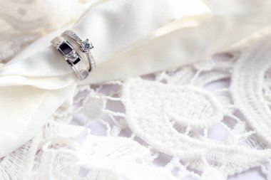 Beyaz masadaki alyans yumuşak odaklı ve arka planda ışık var.