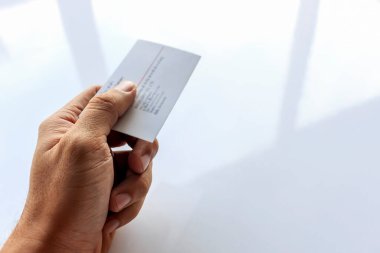 Bir adamın yakın plan eli. Kartviziti yumuşak odaklı ve arka planda ışık var.