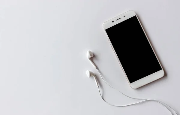akıllı telefon ve kulaklık ışık arka plan üzerinde beyaz masada