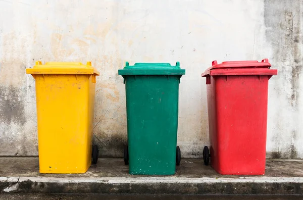 three colorful bins with brick wall background