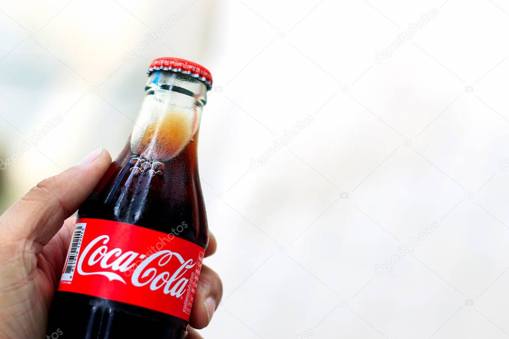 CHIANG RAI  THAILAND - JULY 25, 2016 hand holding glass bottle of coca cola  with soft-focus and over light in the background