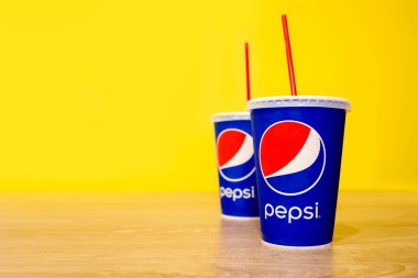 CHIANG RAI, THAILAND-HAZİRAN 24 HAZİRAN 2017, ahşap masa üzerinde sarı duvar zeminli bir fincan pepsi. yumuşak odaklı ve ışığın üzerinde