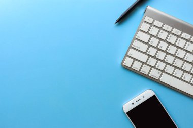 Mesaj alanı, masaüstü bilgisayarı ve mavi ahşap masada akıllı telefonu olan bir iş yeri. ışık üzerinde