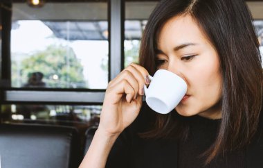 Arka planda yumuşak odaklı kahve içen bir kadın. Işık 01 üzerinde