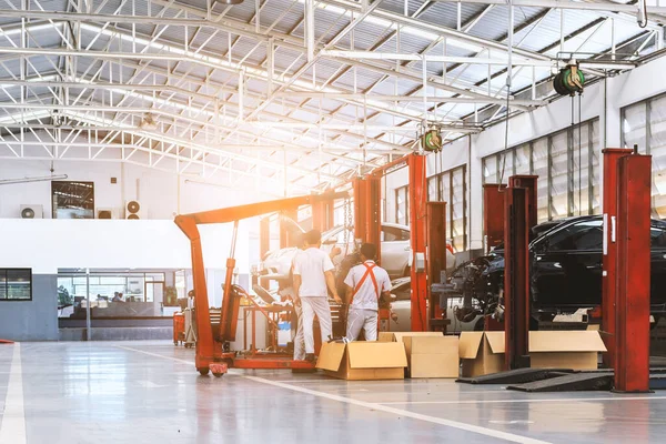 Tamirci, garaj oda servisinde bir arabanın motor bloğunu monte ediyor.