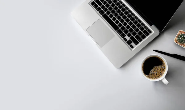 top view of office desk workspace with coffee cup and laptop  on white table background. flat lay