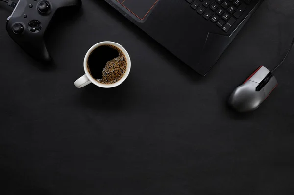 top view of gamer desk workspace with coffee cup and laptop on black table background. flat lay