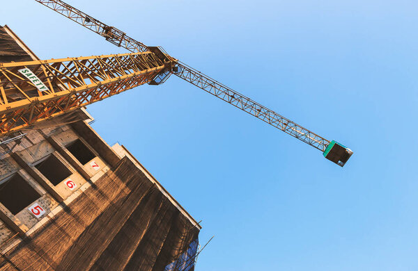 The construction crane and the building with blue sky background and over light