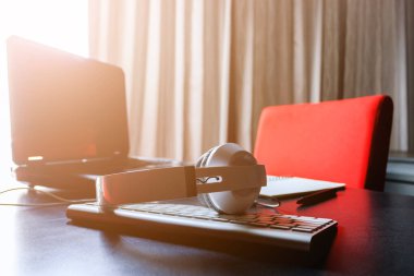 Kulaklıklar, tablet bilgisayarlar ve dizüstü bilgisayarlar siyah masada, arka planda hafif odaklı. gün ışığında