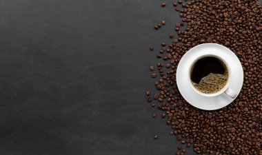 Siyah ahşap masa arkasında bir fincan kahve ve fasulye. en üstteki görünüm