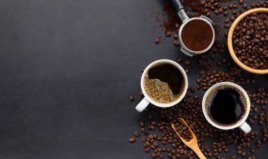 Siyah ahşap masa arkasında bir fincan kahve ve fasulye. en üstteki görünüm