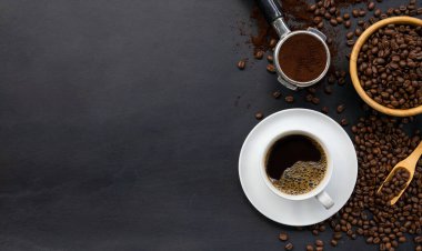 Siyah ahşap masa arkasında bir fincan kahve ve fasulye. en üstteki görünüm