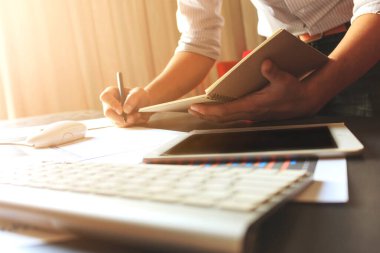 Erkek yönetici, iş yerinde sıcak sonbahar renkleriyle fikir üretiyor ve iş planı yazıyor. Arka planda hafif odaklanma. ışık üzerinde