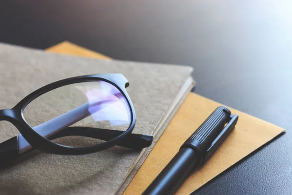 glasses and book on wooden table. film colors tone and soft-focus in the background. over light