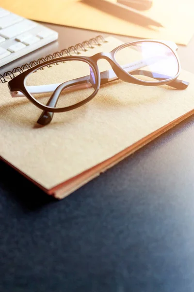 glasses and book on wooden table. film colors tone and soft-focus in the background. over sunlight