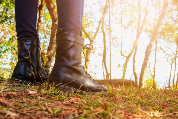 closeup on woman\'s boots, traveler with backpack relaxing outdoor with rocky mountains on background winter vacations and lifestyle hiking concept. warm fall colors. soft-focus and over light