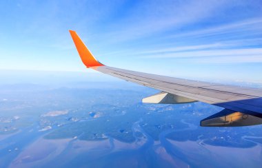 Mavi gökyüzü ve beyaz bulutlu, yumuşak odaklı ve ışığın üzerinde uçak penceresinden görünüm