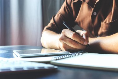 İş yerinde defter, bilgisayar ve tablet üzerinde yazan el işadamlarına yakın çekim. film renkleri tonu, yumuşak odak ve arka plandaki ışık üzerinde