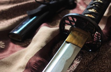 Japon kılıcı sıcak sonbahar renkleriyle saten giyer, arka planda yumuşak odaklanır. ışık üzerinde