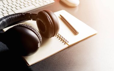 Laptop ve kulaklıklı ofis işyeri ahşap masanın üzerinde sıcak sonbahar renkleri, arka planda hafif odaklanma. ışık üzerinde