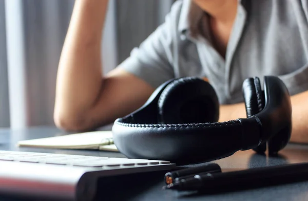 office workplace with laptop and headphone on wood table with warm fall colors, soft-focus in the background. over light