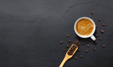 Sıcak espresso ve siyah ahşap masa zemininde kahve çekirdekleri. en üstteki görünüm