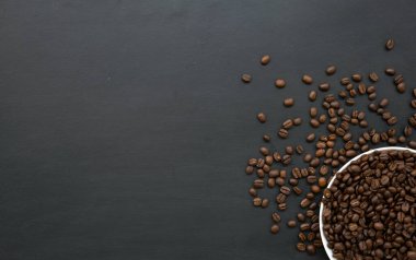 Siyah ahşap zemin üzerinde beyaz fincanda kahve çekirdeği. Üst Manzara. Metin için boşluk