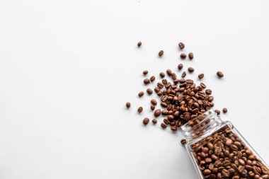 Beyaz masa arkasında cam bir şişedeki kahve çekirdekleri. Üst Manzara. Metin için boşluk
