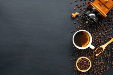 Siyah ahşap masa arkasında bir fincan kahve ve fasulye. en üstteki görünüm