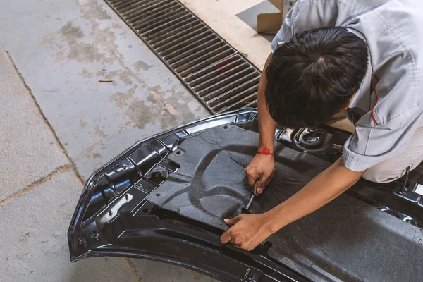 mechanic fixing car door and body paint with soft-focus and over light in the background