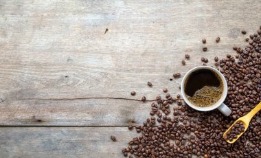 Ahşap zemin üzerinde bir fincan kahve ve fasulye. en üstteki görünüm