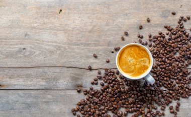 Ahşap zemin üzerinde bir fincan kahve ve fasulye. en üstteki görünüm