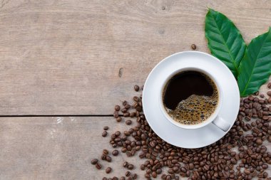 Ahşap zemin üzerinde bir fincan kahve ve fasulye. en üstteki görünüm