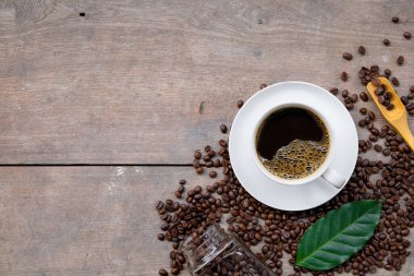 Ahşap zemin üzerinde bir fincan kahve ve fasulye. en üstteki görünüm