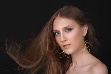 Büyük altın küpeli güzel bir kızın portresi. Siyah arka planda izole edilmiş. Moda, tarz